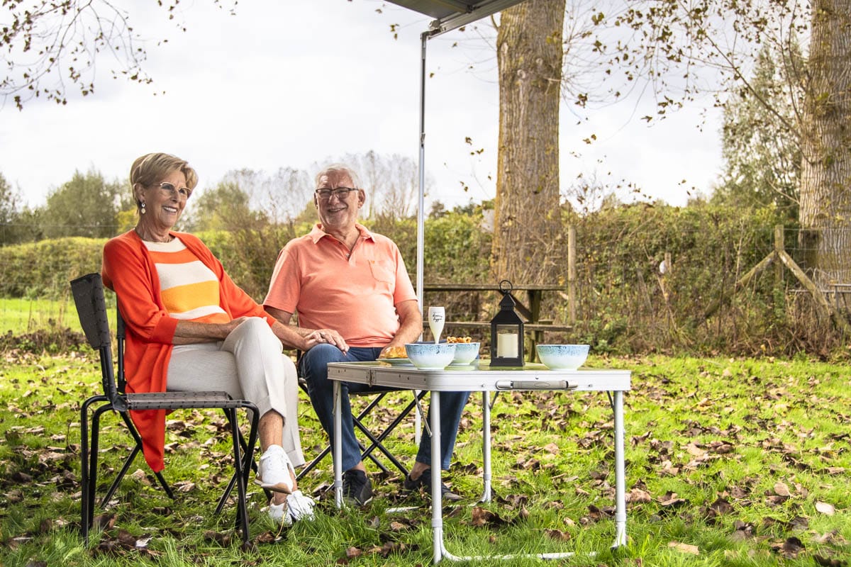 Oudere koppel geniet van een gezellige picknick naast hun Reislust camper, echte vrijheid onderweg.
